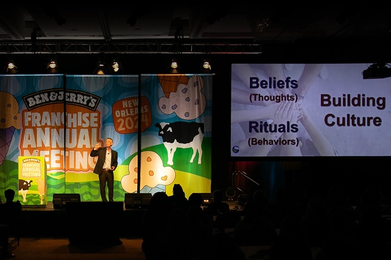 scott greenberg standing on stage in front of Ben & Jerry's banner at annual 2024 franchise meeting